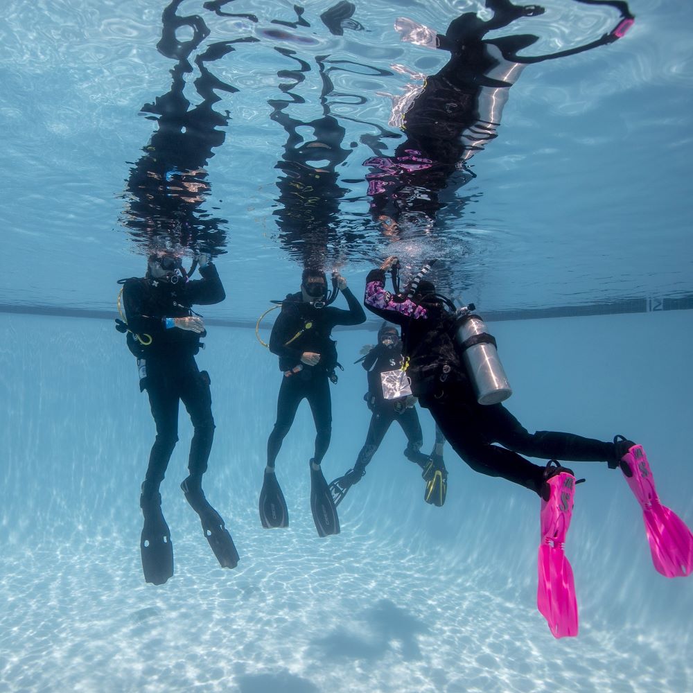 Instructor helping a new diver with simple gear setup
